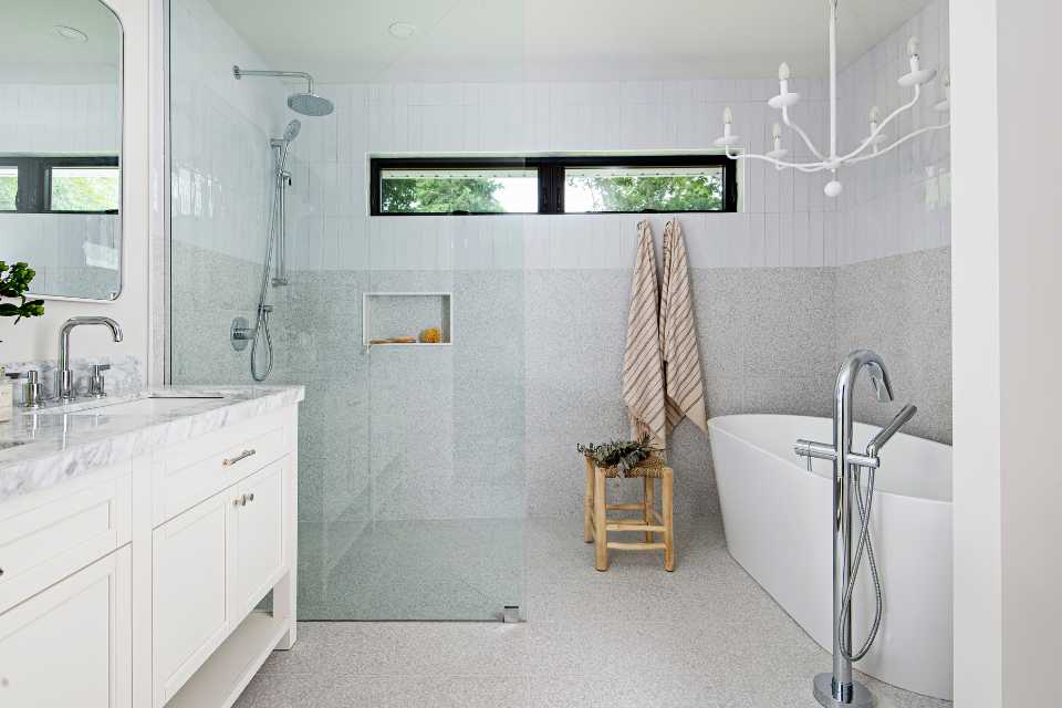 primary bathroom suite with deep soak tub, white chandelier, and marble countertop